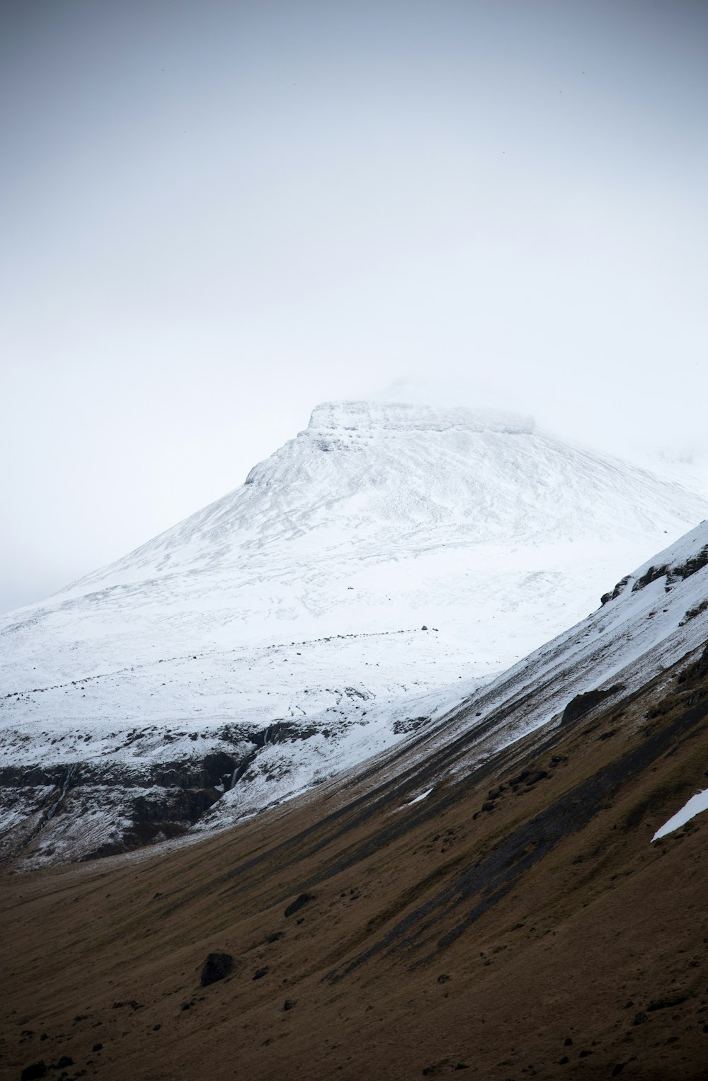 a mountain covered in snow with a sky background