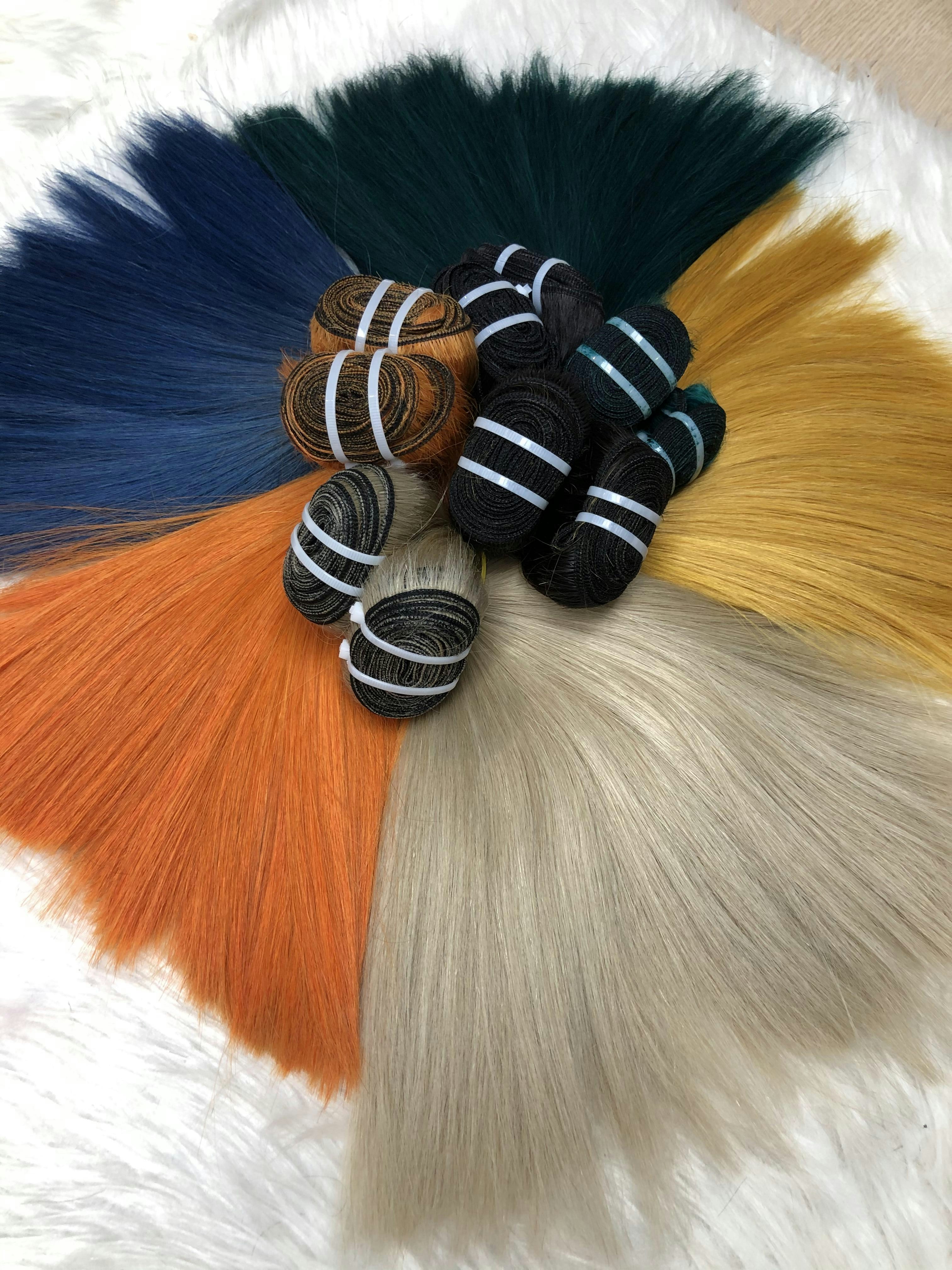 Colorful hair extensions arranged in a circular pattern on white fur.