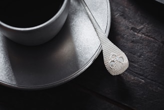 Close-up of a stylish ceramic mug and wooden spoon resting on a suede-colored placemat.
