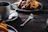 Close-up of a steaming cup of coffee next to a freshly baked slice of pie on a rustic wooden table.