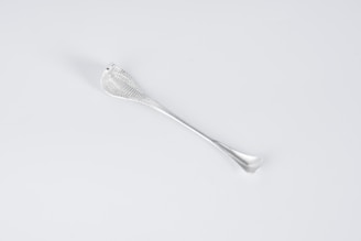 A sleek, metallic utensil with a textured handle. The design is minimalist, with a smooth, reflective surface and elegant curves.