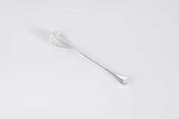 A sleek, metallic utensil with a textured handle. The design is minimalist, with a smooth, reflective surface and elegant curves.