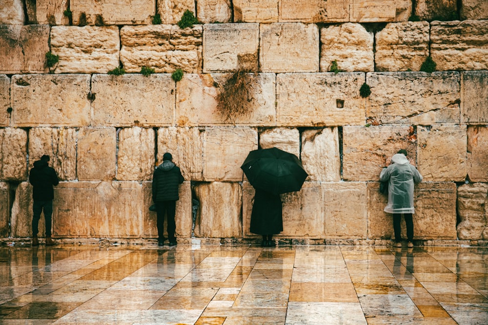 a group of people standing next to a stone wall