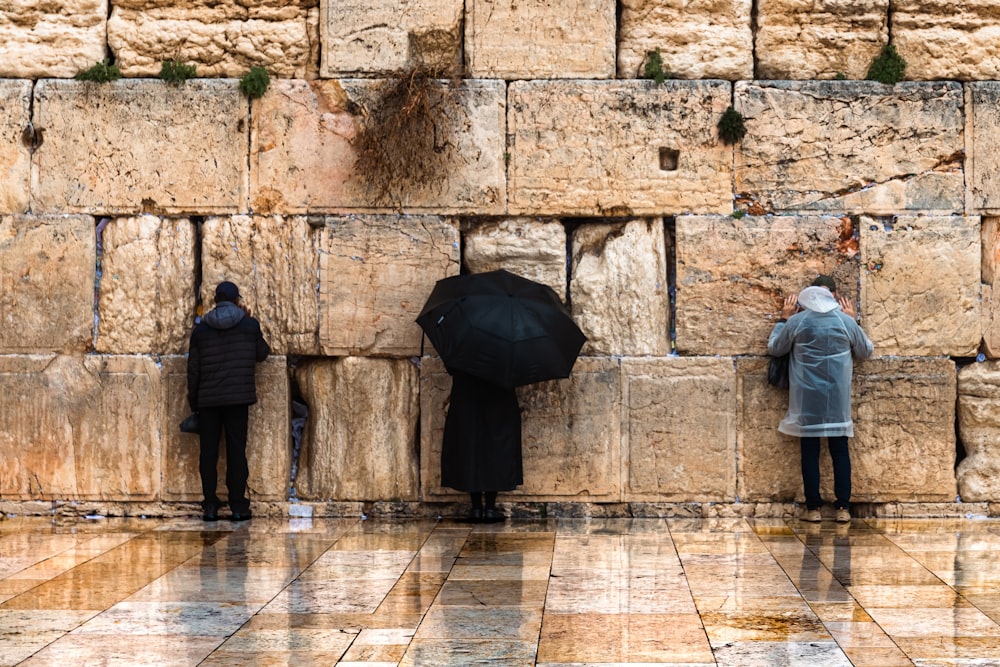 a group of people standing next to a stone wall