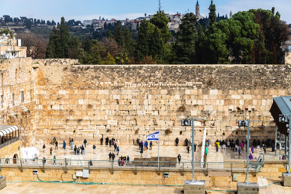 um grupo de pessoas em pé na frente de um muro de pedra