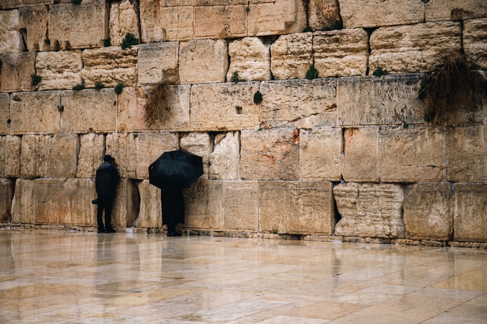 a couple of people standing next to a wall