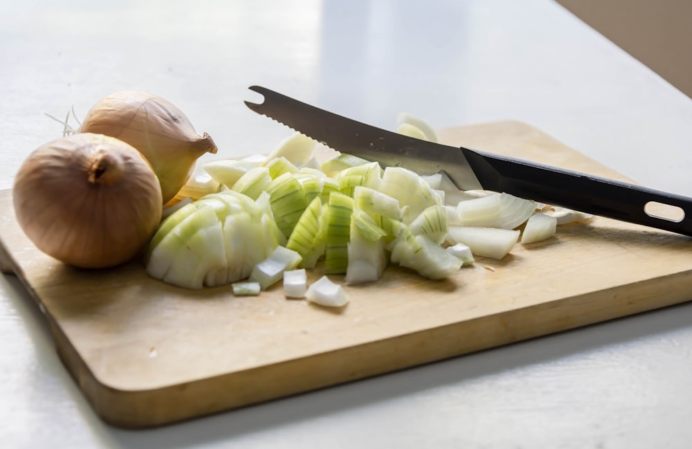 a cutting board with onions and a knife on it