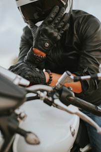 a man in a leather jacket and helmet on a motorcycle