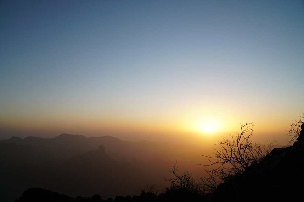 the sun is setting over a mountain range