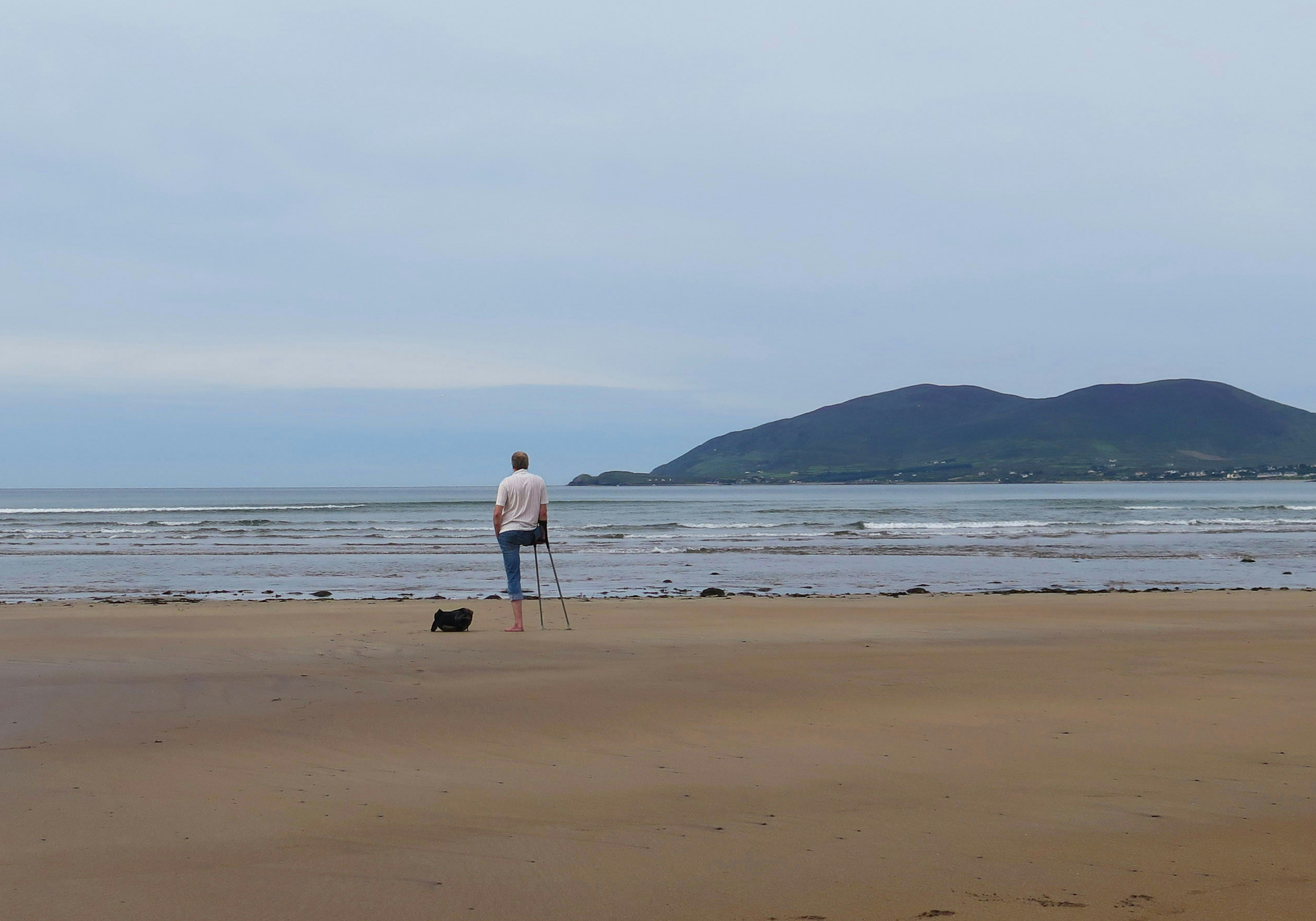 a man standing on top of a sandy beach next to the ocean, 