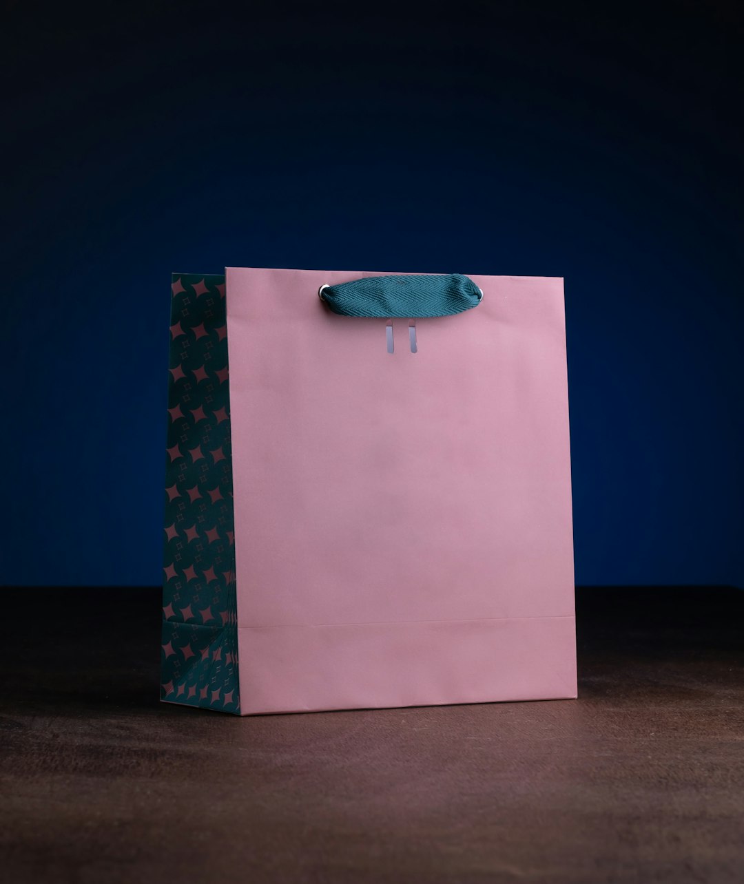 Closeup shot of a pink paper shopping bag on a dark background on top of a wooden table