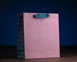 a pink shopping bag with a blue handle