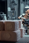 a robot holding a gun next to a pile of rolls of toilet paper