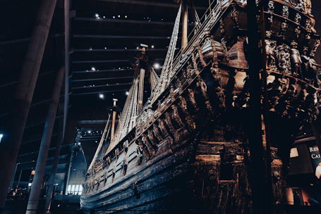 Restored wooden vessel displayed against a textured wall, highlighting fine craftsmanship.