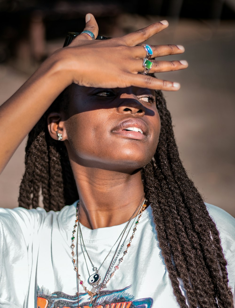 a woman with dreadlocks holding her hand up to her face