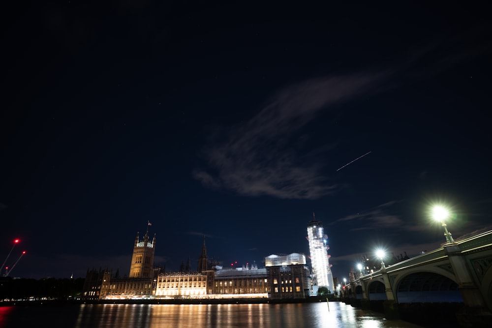 a night view of a city with a bridge and a clock tower