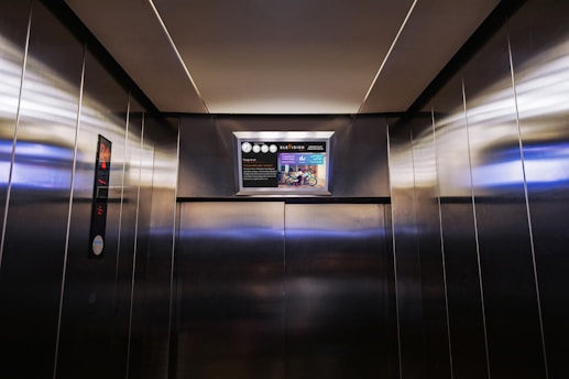 a metallic elevator with a poster on the wall