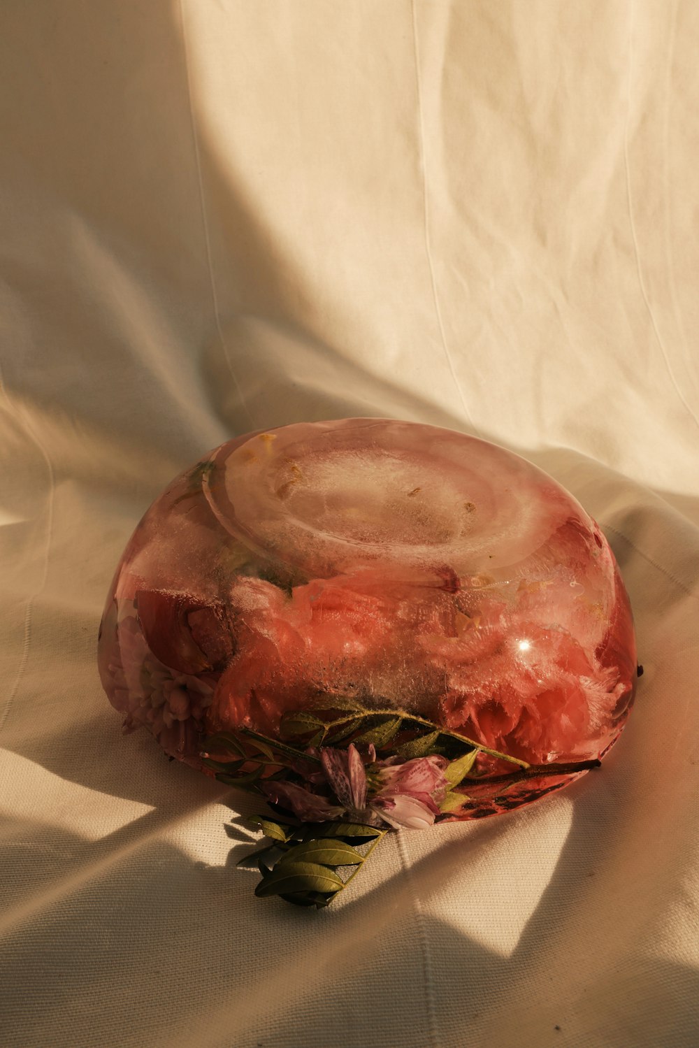 a pink vase sitting on top of a white sheet