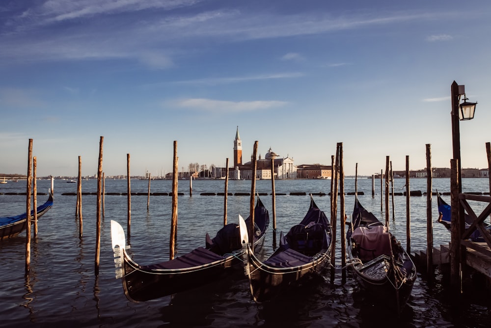 a row of gondolas tied to poles in the water