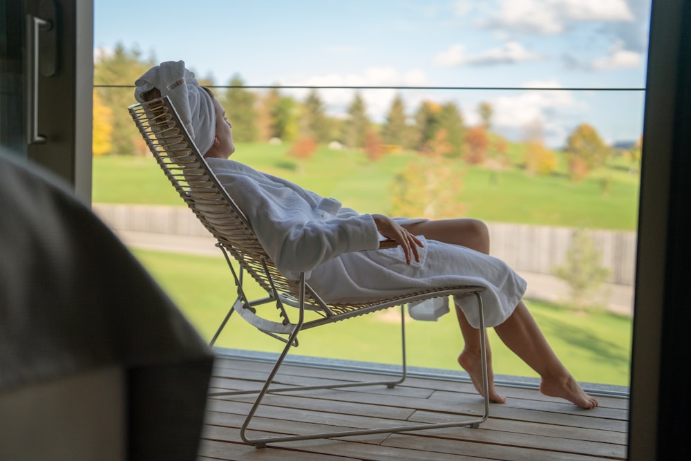 a woman sitting in a chair looking out a window