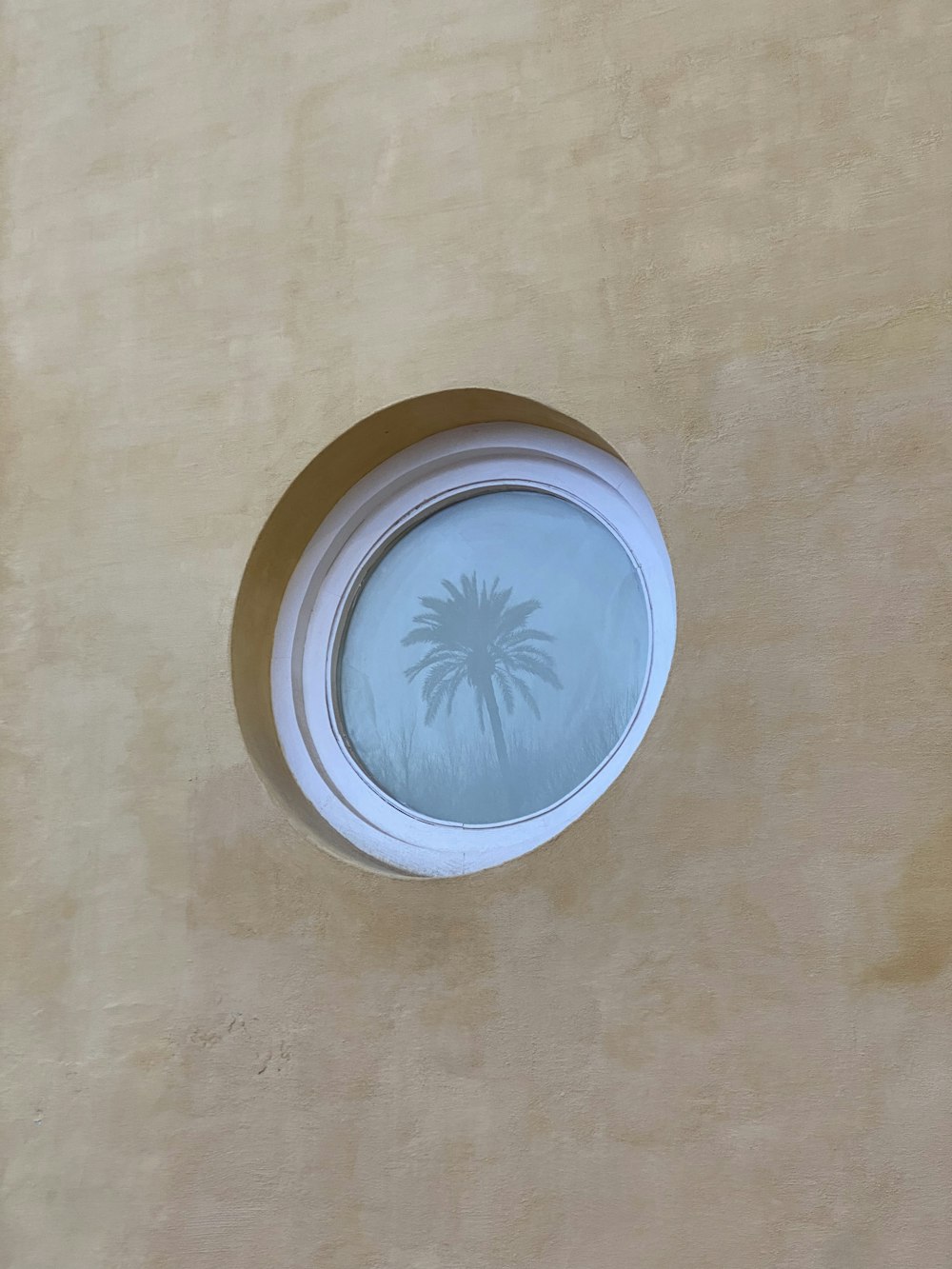 una ventana redonda con una palmera dibujada en ella