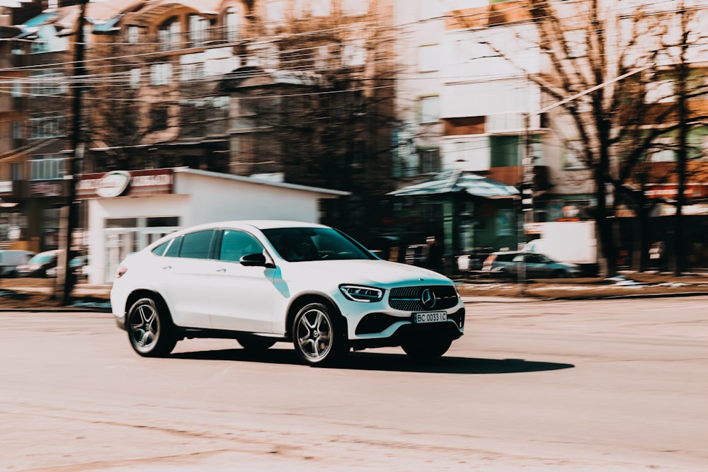 a white car driving down a street next to tall buildings