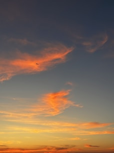 An airplane soaring above the clouds during sunset.