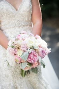 a bride holding a bouquet of pink and white flowers