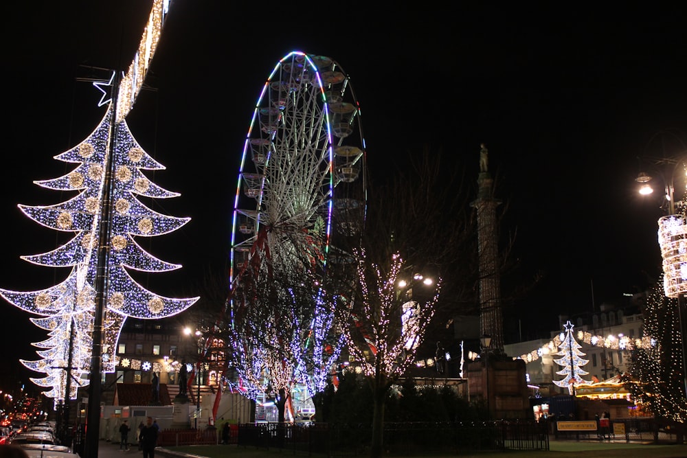 uma roda gigante cercada por luzes de Natal e árvores