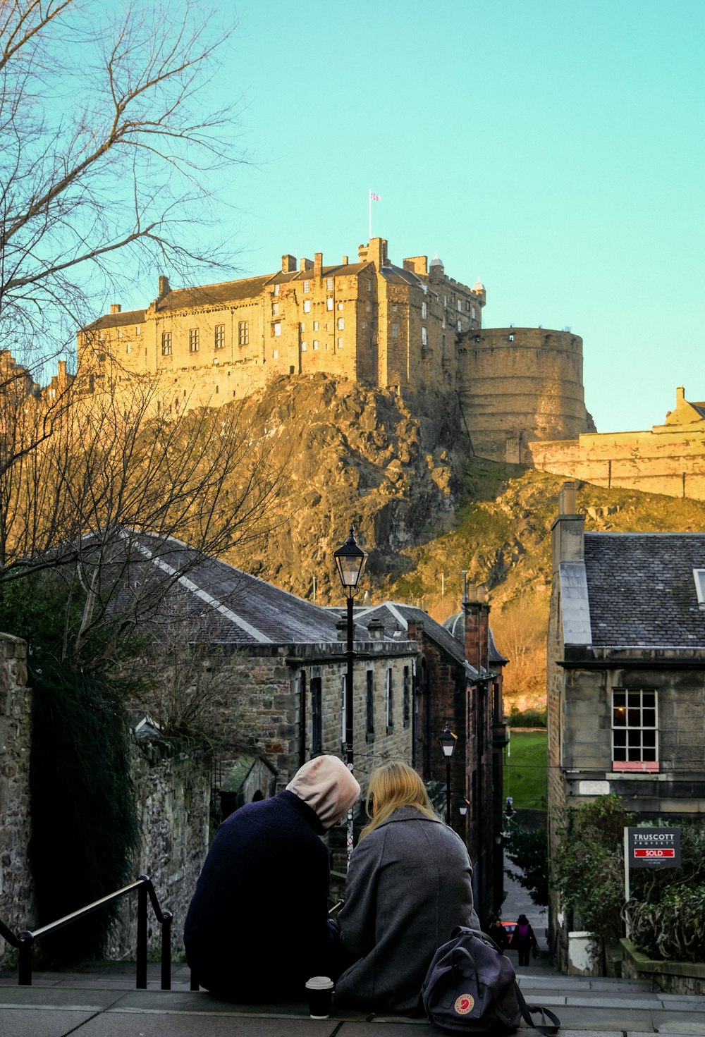 two people sitting on a bench in front of a castle