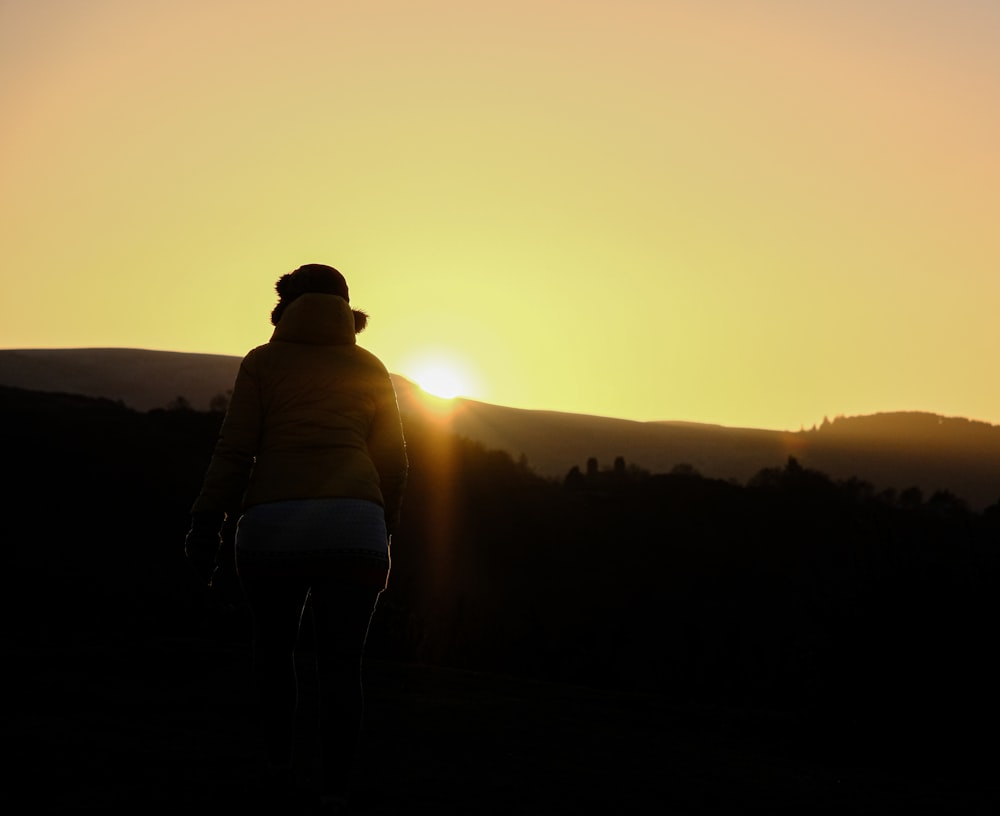 Una donna che cammina nel tramonto con le spalle alla macchina fotografica  foto – Collina di Blackford Immagine gratuita su Unsplash