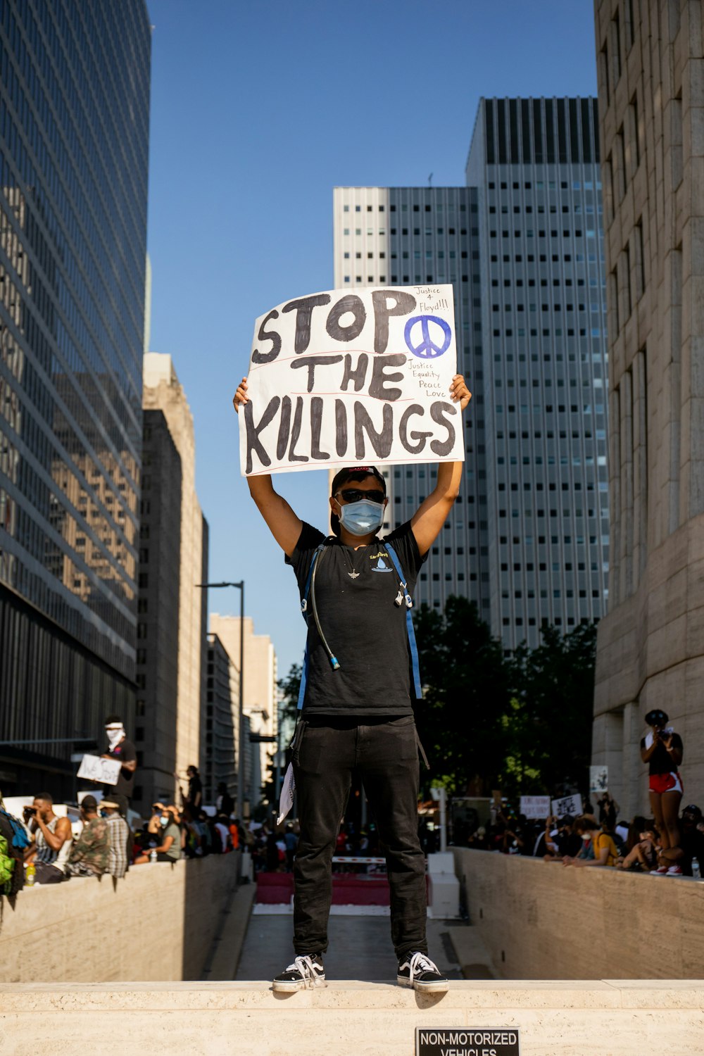 a man holding a sign that says stop the killings