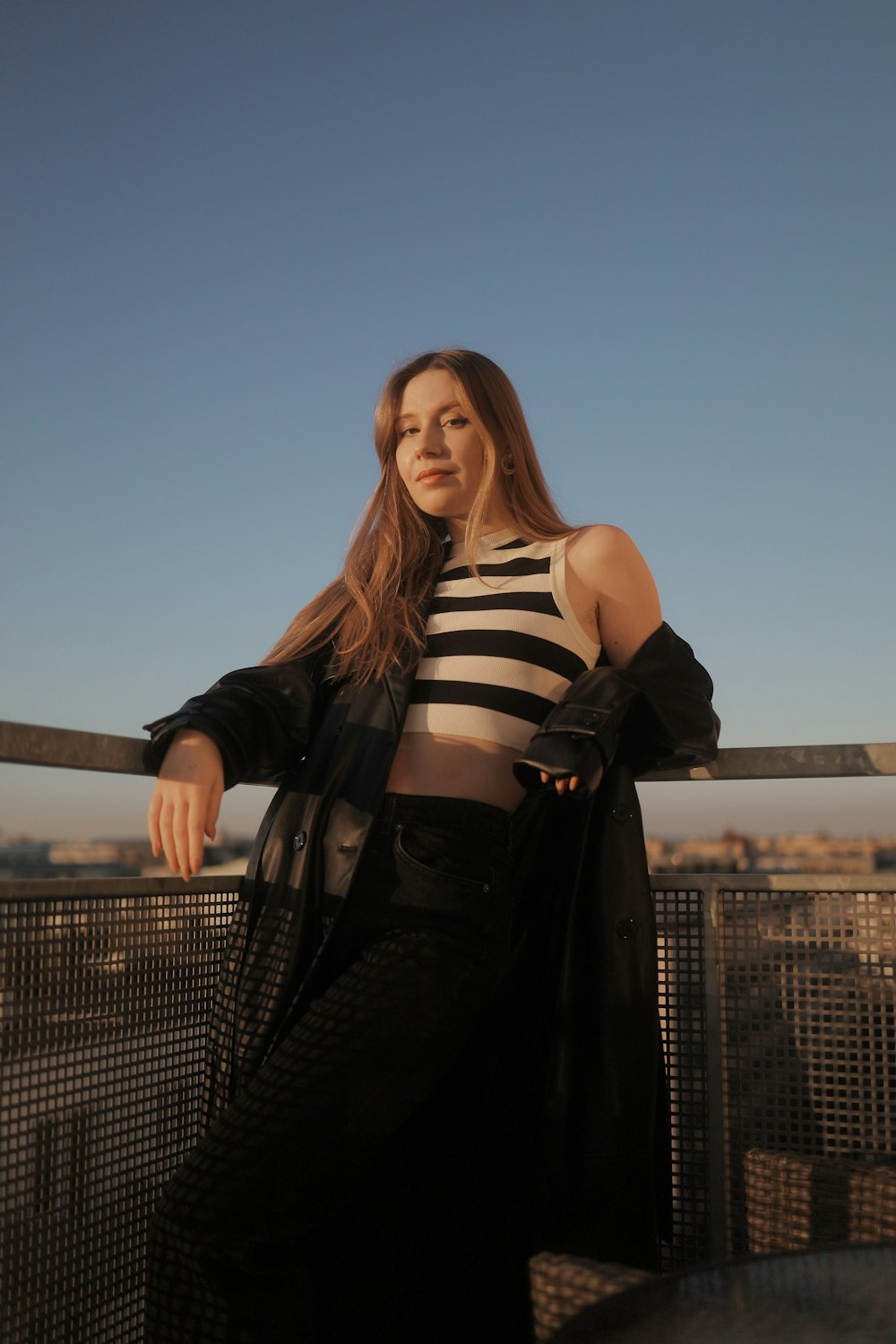 a woman standing on top of a roof next to a fence