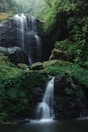 a waterfall in the middle of a lush green forest