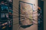 A wall display featuring a map in the center with strings connecting various photographs on either side, suggesting an investigative or planning scenario.