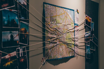 A wall covered in pinned photos, newspaper clippings, and red string connecting clues.