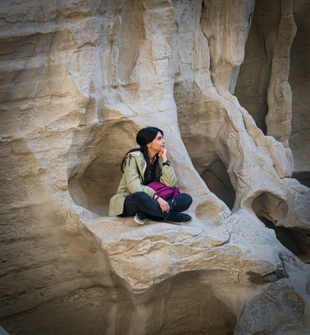 a woman is sitting on a rock formation