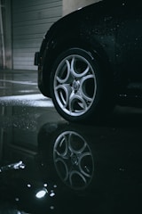 Close-up of a sleek blacked-out car wheel shining under soft lighting.