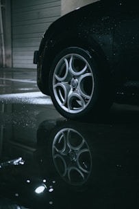 Close-up of a sleek blacked-out car wheel shining under soft lighting.