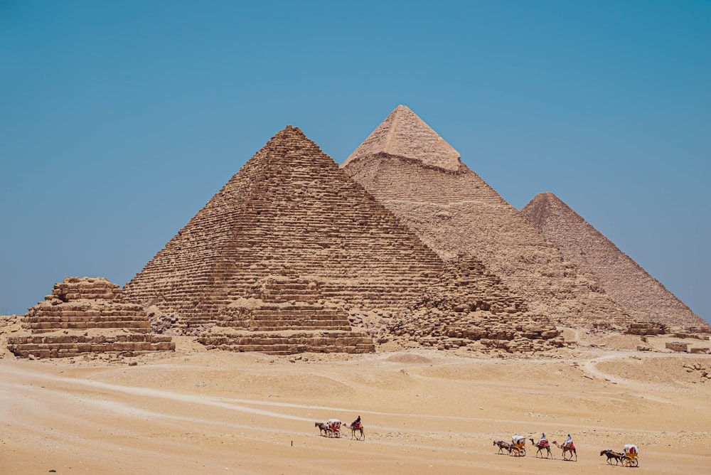 a group of people riding horses next to the pyramids of giza