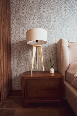 Warmly lit bedroom corner showcasing tailored wooden bedside tables and textured fabrics.