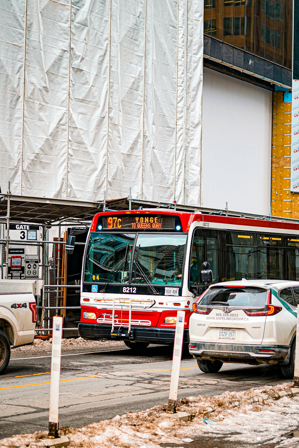 a red bus driving down a street next to a tall building