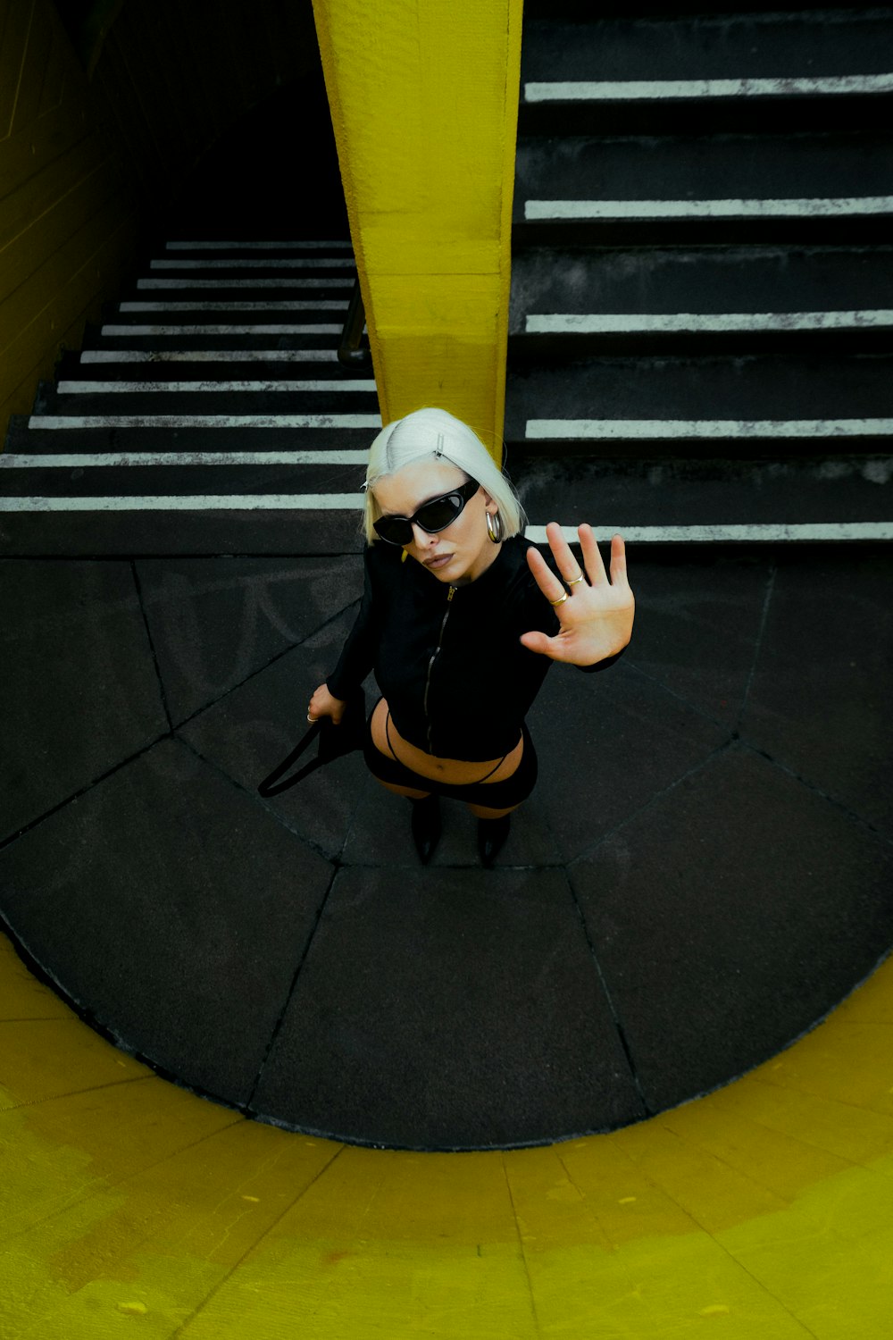 a woman with white hair and sunglasses is standing in front of some stairs