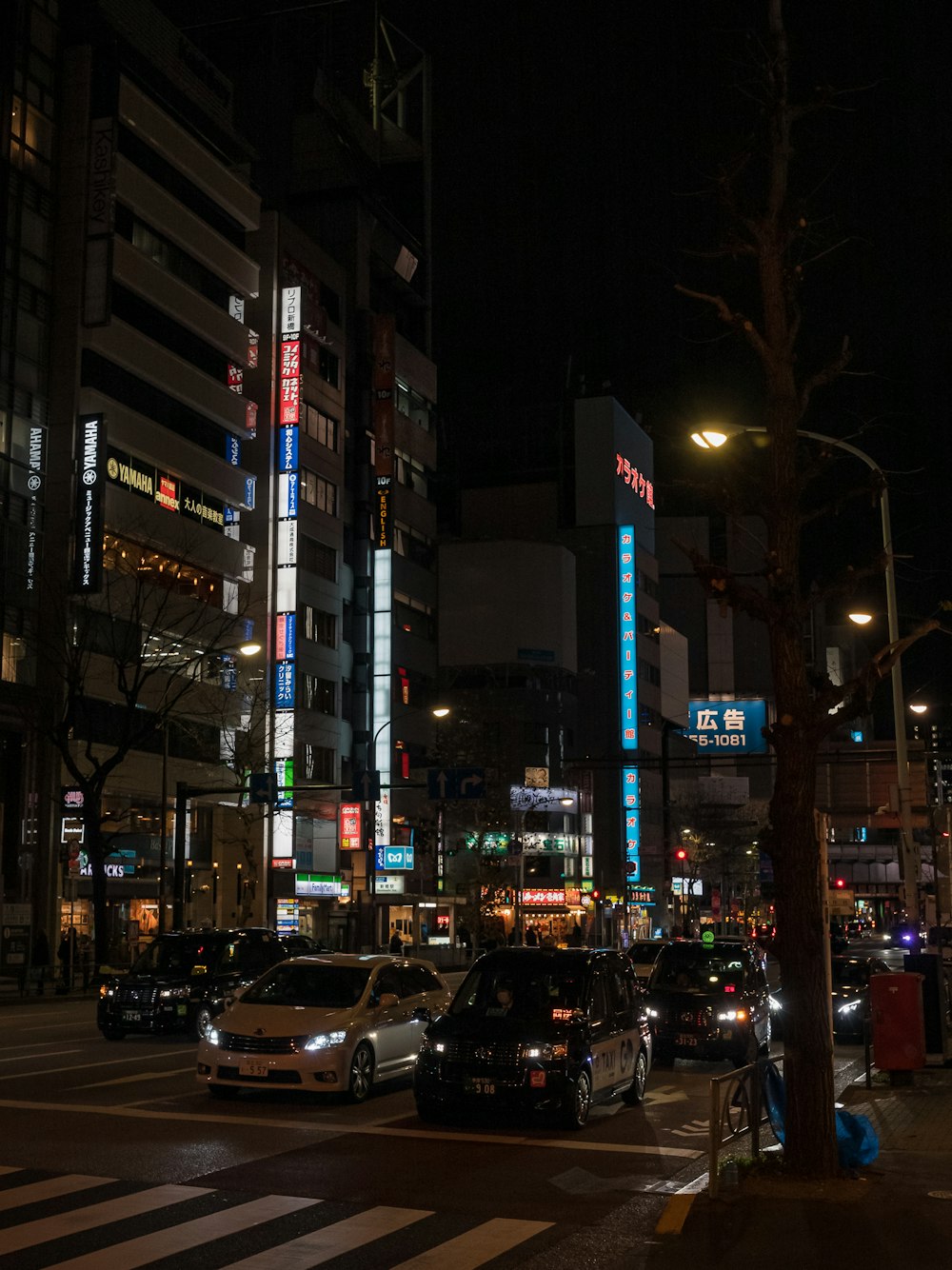 a city street at night with cars parked on the side of the road