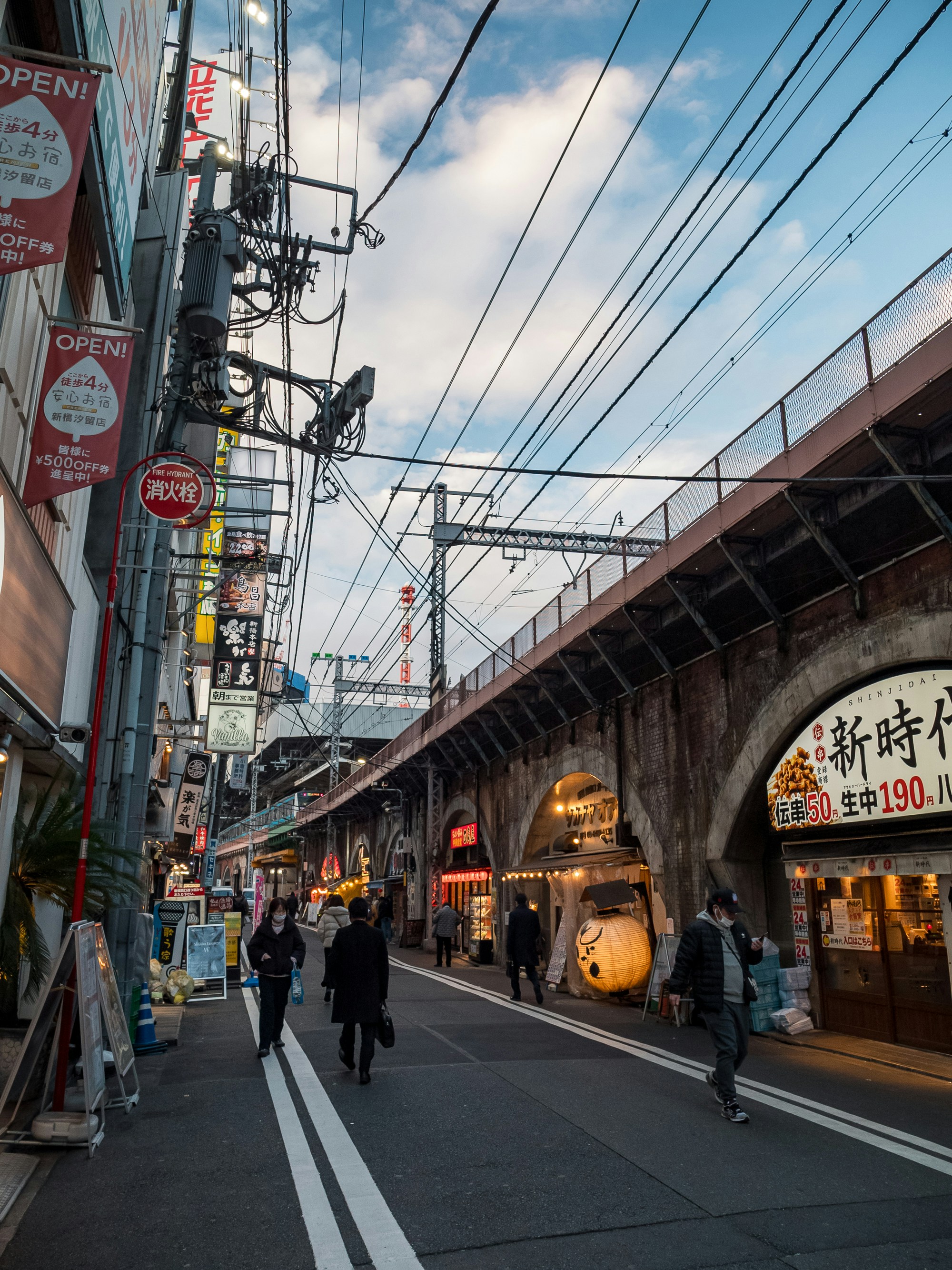 a group of people walking down a street next to a train station