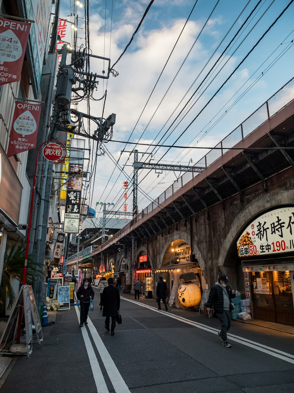 a group of people walking down a street next to a train station