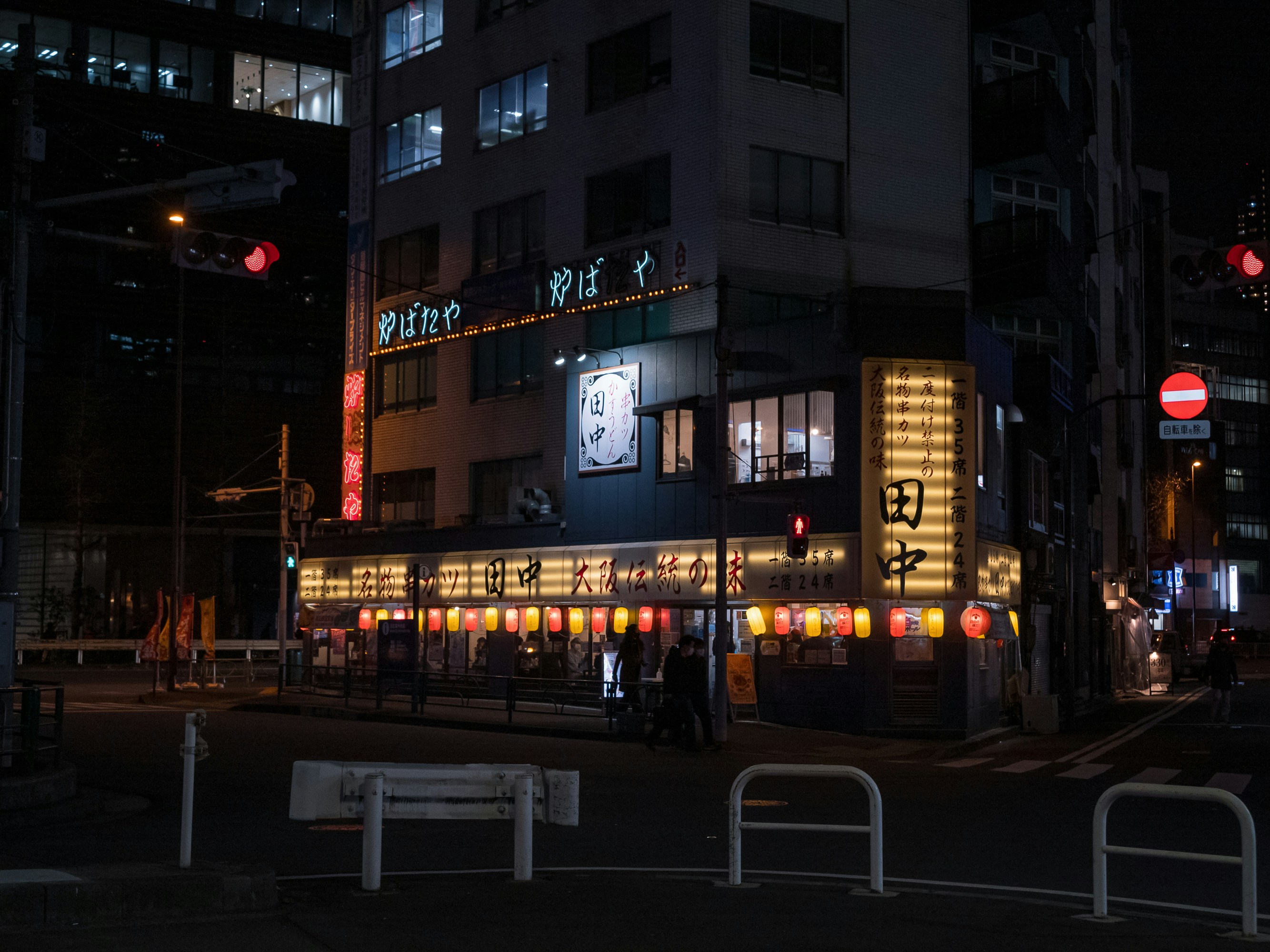 a city street at night with a building lit up, 