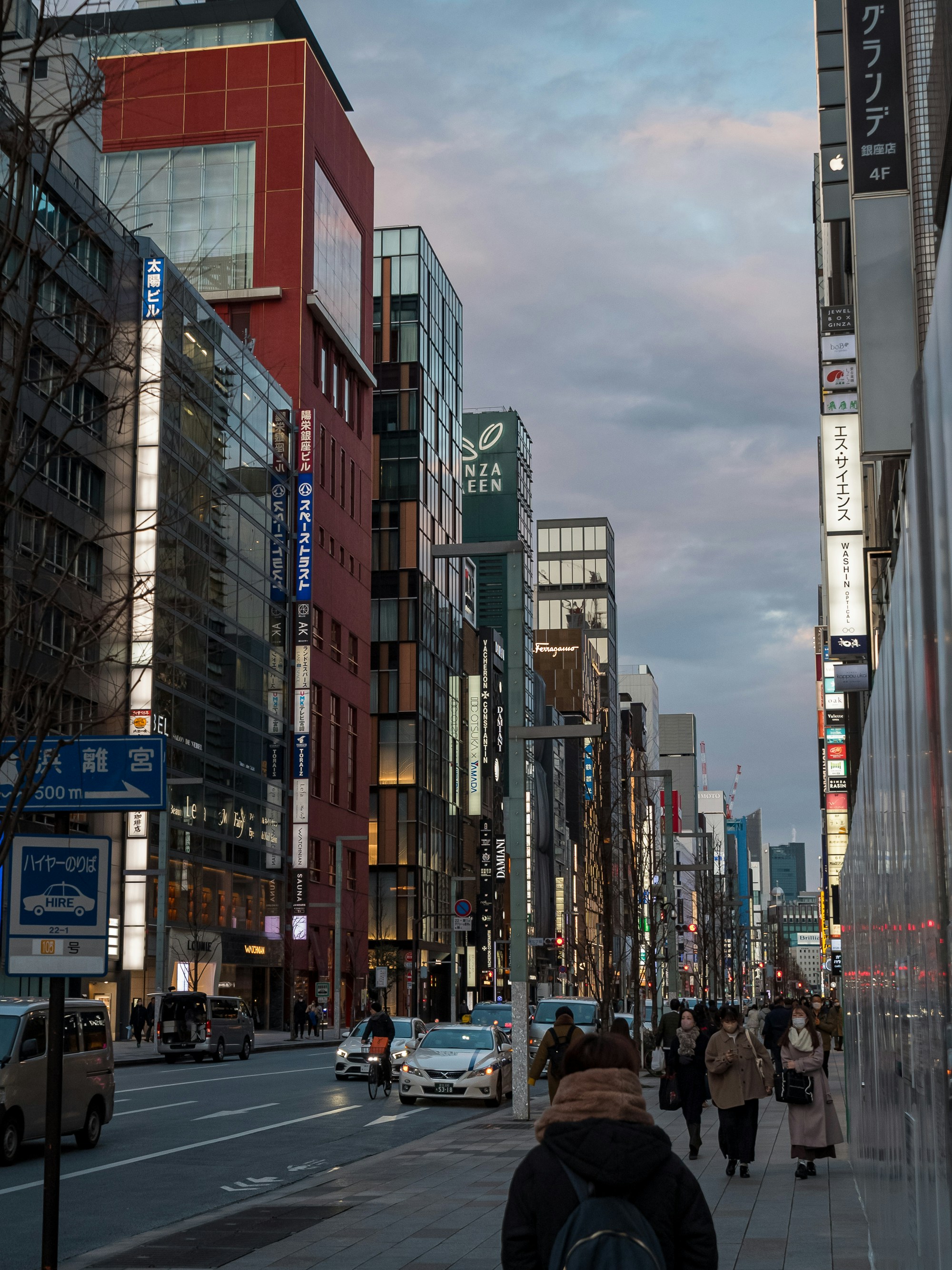 a group of people walking down a street next to tall buildings