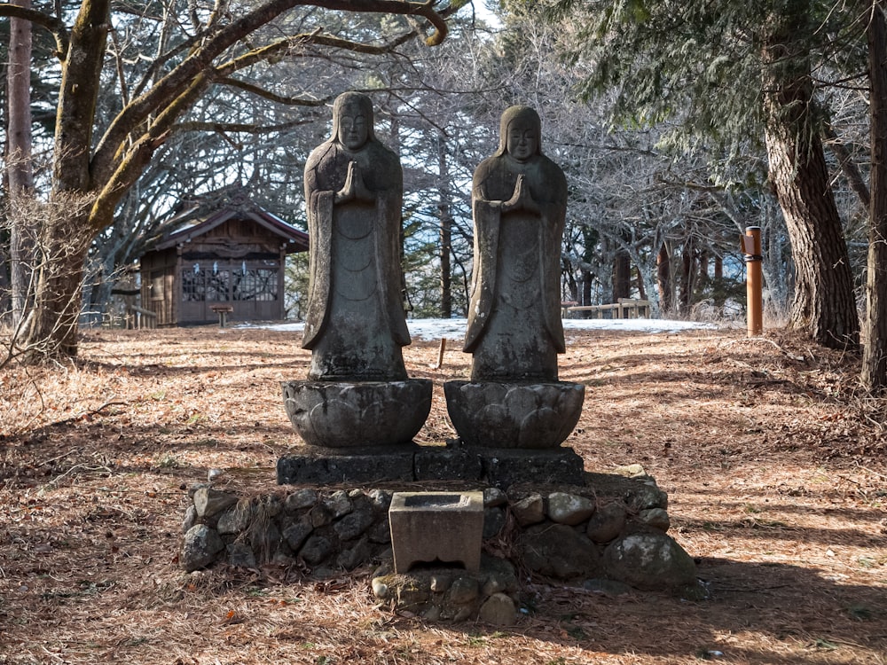 a couple of statues sitting in the middle of a forest