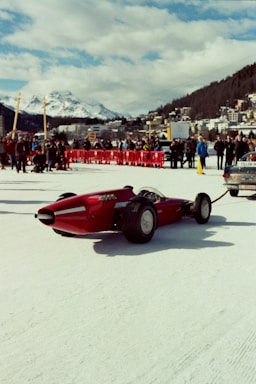 a red car pulling a trailer on a snowy surface
